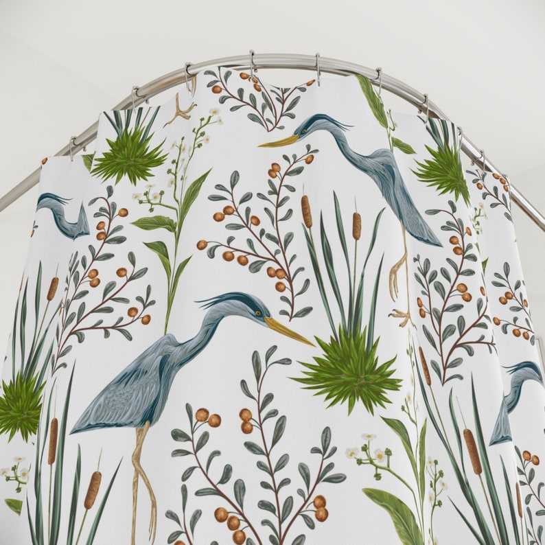 May include: White shower curtain with a repeating pattern of blue herons, green reeds, and brown berries.