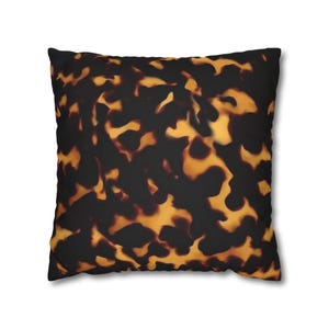 May include: Square throw pillow with a tortoiseshell pattern. The pillow features a repeating design of dark brown and golden-yellow shapes, creating a mottled effect. The pillow is a decorative home accessory.