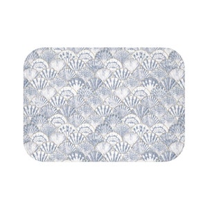 May include: A white rectangular placemat with a blue and gold seashell pattern.