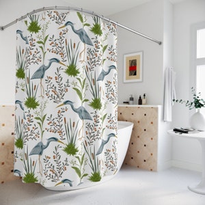 May include: White shower curtain with a repeating pattern of blue herons, green reeds, and brown berries.