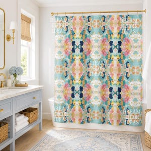 May include: A shower curtain featuring a vibrant, abstract watercolor pattern in shades of pink, teal, navy blue, and yellow. The design is symmetrical and repetitive, with the text DREAM DECOR IDEAS overlaid in white across the fabric surface.