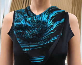 Puede incluir: Una blusa negra sin mangas con una bufanda de seda estampada en azul y negro. La bufanda presenta un diseño abstracto y arremolinado con tonos de azul y turquesa. La mujer tiene la piel clara y el pelo rubio.