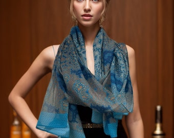 May include: A woman wearing a blue and brown patterned scarf with a black sleeveless dress. The scarf has a geometric design.