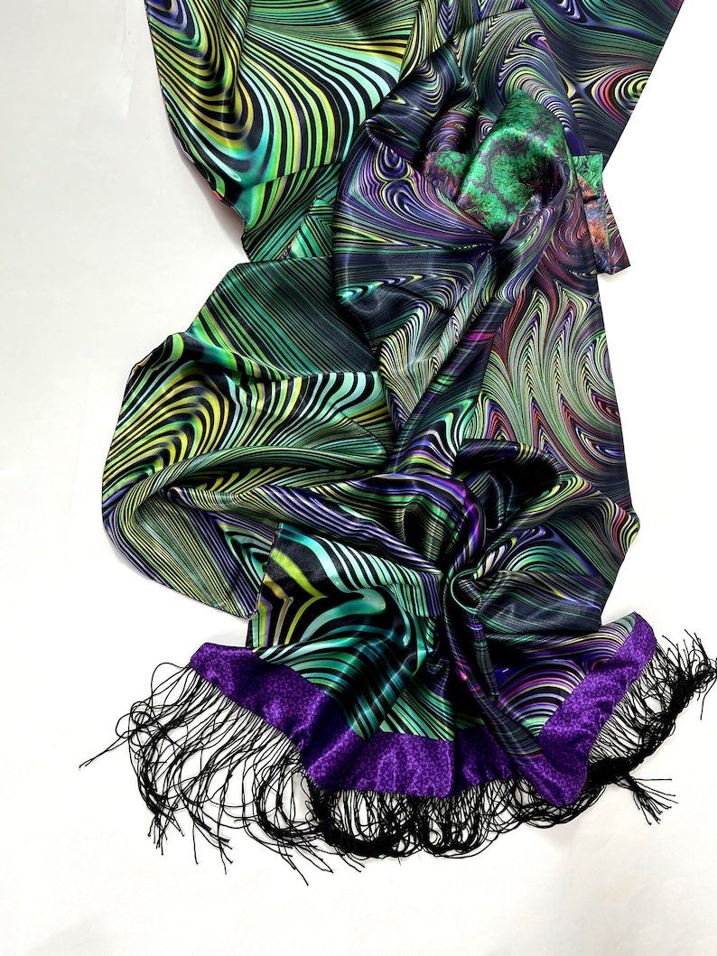 May include: A black silk scarf with a green, purple and yellow abstract pattern. The scarf has a purple trim and black fringe.