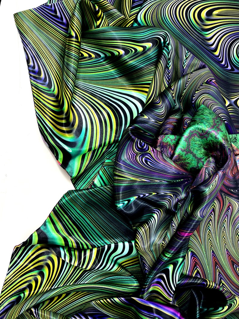 May include: A green, black and yellow patterned fabric with a swirling, abstract design. The fabric is made of a silky material and has a smooth texture.