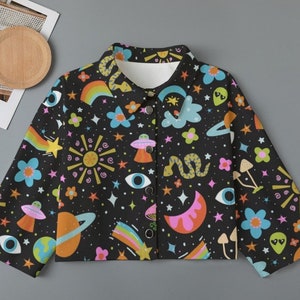 May include: Black button-up jacket with a colorful, whimsical print. The design features planets, rainbows, stars, flowers, UFOs, and other celestial and psychedelic elements. The jacket has a classic collar and long sleeves.