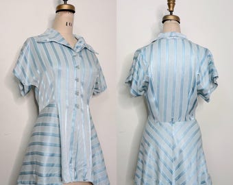May include: Light blue striped dress with short sleeves and a collared neckline. The dress features vertical stripes on the bodice and skirt, with a button-down front. The fabric has a subtle sheen, giving it a vintage look.