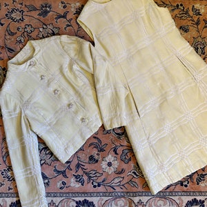 Peut inclure: Un ensemble robe et veste à carreaux jaunes et blancs. La robe est sans manches et a un corsage ajusté. La veste a des manches longues et une fermeture à boutons.