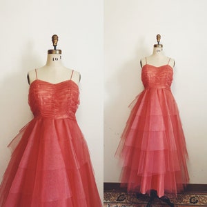 Pode incluir: Um vestido vintage de tule rosa com saia em camadas e corpete ajustado. O vestido está em um manequim e tem um decote em coração.
