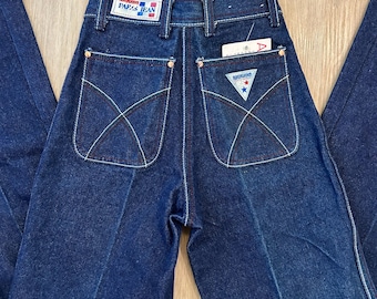 May include: A pair of dark blue denim jeans with a red, white, and blue "Paris Jean" label on the back waistband. The jeans have a high waist and a straight leg.