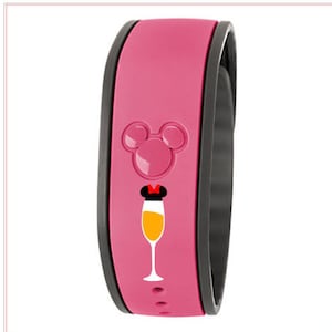 May include: Pink MagicBand with a black Mickey Mouse silhouette and a champagne glass with a red bow on top. The MagicBand has a black band around the edge.