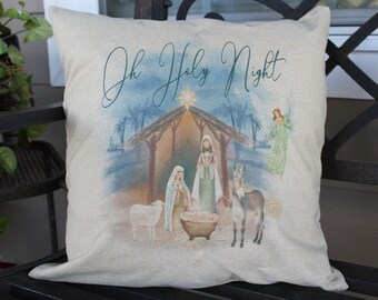 May include: A decorative pillow with a Christmas scene. The pillow features an illustration of the nativity scene with the text "Oh Holy Night" in a script font. The image includes Mary, Joseph, baby Jesus, an angel, and animals.