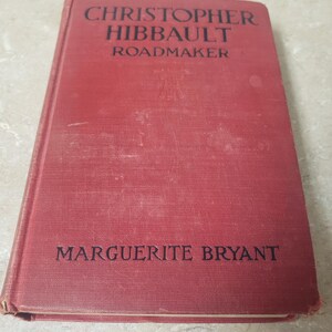 May include: A red hardcover book with the title "Christopher Hibbault Roadmaker" and the author "Marguerite Bryant" printed on the front cover.