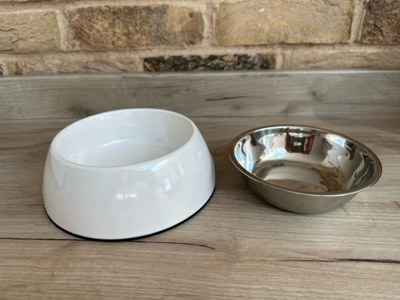May include: Two pet bowls, one white ceramic and one silver metal.