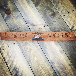 May include: A wooden sign with a lighthouse illustration and the coordinates "N41&deg; 36' 19.54" and "W71&deg; 18' 17.85" engraved on it.