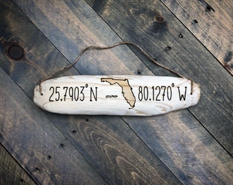 May include: A wooden sign with the outline of the state of Florida and the coordinates 25.7903° N - 80.1270° W.