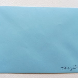 May include: A light blue envelope with the text "Sky Blue." written in black ink.