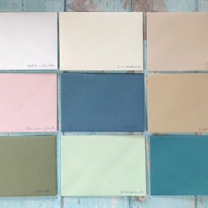 May include: Nine color swatches of cardstock paper in various shades of white, pink, blue, green, and brown. The swatches are labeled with the following names: Soft White, Limestone,  Clotted Cream, Blush Pink, Slate, Cafe Latte, Olive, Pistachio, and Teal.