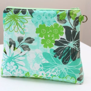 May include: A green and white floral print zipped pouch with a small silver loop handle.