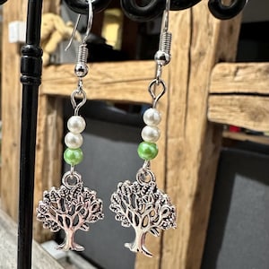 May include: Silver tree of life earrings with green and white pearl beads.