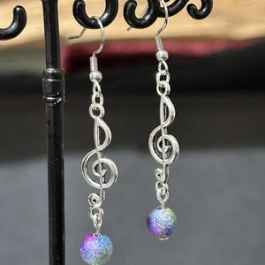Silver metal earrings with treble clef, musical note and multi-colored magic beads