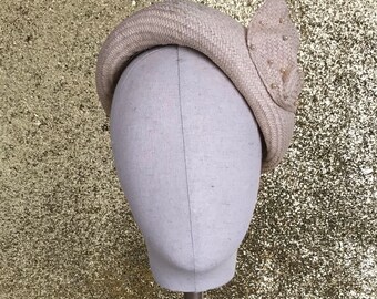 May include: A white straw hat with a decorative bow on the side. The bow is made of white straw and has small white beads.