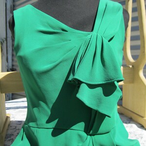 May include: A green sleeveless dress with a bow detail at the neckline. The dress has a fitted bodice and a flowing skirt.