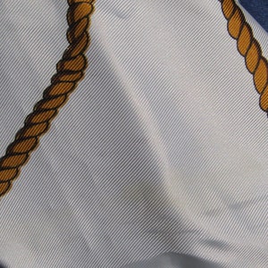 May include: A white fabric with two brown rope designs. The fabric has a subtle texture and is folded over on itself.