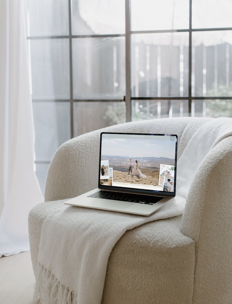 May include: A laptop computer with a white background open to a website with the text "Your love story, one moment at a time" and images of a couple in a desert landscape.