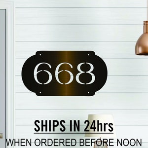 May include: Dark bronze metal house number plaque with the number 668 in white lettering. The plaque is oval shaped and has a brushed metal finish. The text "SHIPS IN 24hrs WHEN ORDERED BEFORE NOON FOR 11/27-12/25 SEE APPROX SHIP & DELIVERY DATE FOR YOUR ZIP CODE BELOW BEFORE ORDERING" is printed below the plaque.