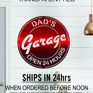 Pode incluir: Um sinal de metal vermelho com o texto "DAD'S Garage OPEN 24 HOURS" em letras brancas. O sinal &eacute; circular e tem um aspecto desgastado. O texto "SHIPS IN 24hrs WHEN ORDERED BEFORE NOON FOR 11/27-12/25 SEE APPROX SHIP & DELIVERY DATE FOR YOUR ZIP CODE BELOW BEFORE ORDERING" est&aacute; impresso abaixo do sinal.