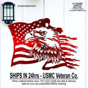 May include: A red metal wall art piece depicting an American flag with a bald eagle. The eagle's head is in profile, with detailed feathering. The flag features stars and stripes. The text "14 GAUGE AMERICAN MADE STEEL" is also visible.