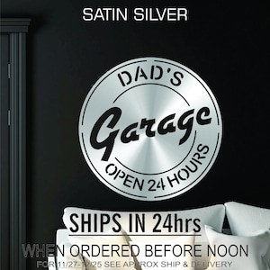 Pode incluir: Uma placa de metal prateada com o texto "DAD'S Garage OPEN 24 HOURS" em um design circular. A placa tem um acabamento de metal escovado e &eacute; perfeita para uma garagem ou oficina.