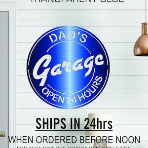 Pode incluir: Uma placa de metal azul com o texto "DAD'S Garage OPEN 24 HOURS" em letras brancas. A placa tem uma superf&iacute;cie brilhante e reflexiva. O texto "SHIPS IN 24hrs" est&aacute; escrito em preto abaixo da placa. O texto "WHEN ORDERED BEFORE NOON FOR 11/27-12/25 SEE APPROX SHIP & DELIVERY DATE FOR YOUR ZIP CODE BELOW BEFORE ORDERING" est&aacute; escrito em preto abaixo da placa.