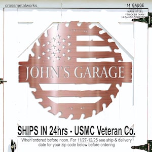 Op de afbeelding: Een koperkleurig metalen bord met de tekst "JOHN'S GARAGE" en een ontwerp van de Amerikaanse vlag. Het bord is uitgesneden in de vorm van een zaagblad. De tekst "14 GAUGE AMERICAN MADE STEEL" is ook zichtbaar.