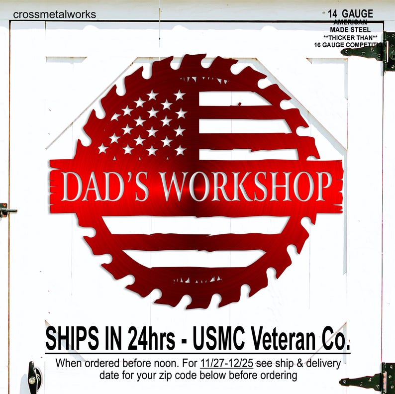 Op de afbeelding: Een rood metalen bord met de tekst "DAD'S WORKSHOP" in een gestileerd lettertype. Het bord heeft de vorm van een zaagblad en toont het ontwerp van de Amerikaanse vlag. Het bord is gemaakt van 14 gauge Amerikaans staal.