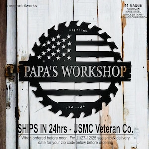 May include: Black metal sign with a saw blade design, featuring the American flag and the text "PAPA'S WORKSHOP." The sign is made of 14-gauge American-made steel.