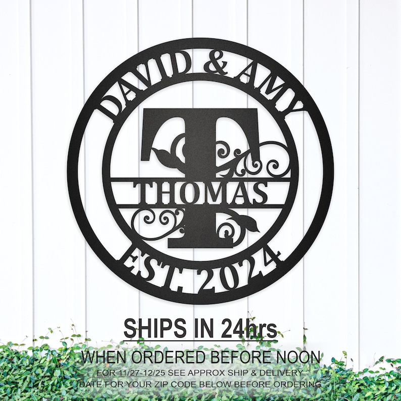 May include: Black metal round sign with the names David & Amy, the initial T for Thomas, and the year 2024. The sign has a decorative floral design.