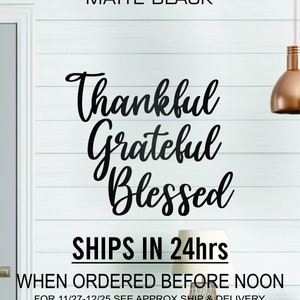 May include: Matte black vinyl wall decal with the words "Thankful Grateful Blessed" in a cursive font. The decal is shown on a white wood background. The text "SHIPS IN 24hrs WHEN ORDERED BEFORE NOON FOR 11/27-12/25 SEE APPROX SHIP & DELIVERY DATE FOR YOUR ZIP CODE BELOW BEFORE ORDERING" is also included.