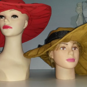 Op de afbeelding: Twee breedgerande hoeden op mannequins. De hoed links is rood en de hoed rechts is bruin.