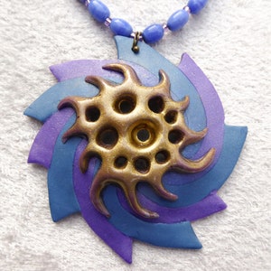 A swirl of blue and sparkly purple polymer clay. Shiny gold polymer clay 3D net. Blue oval glass beads. Bronze colored clasp and chain. image 2