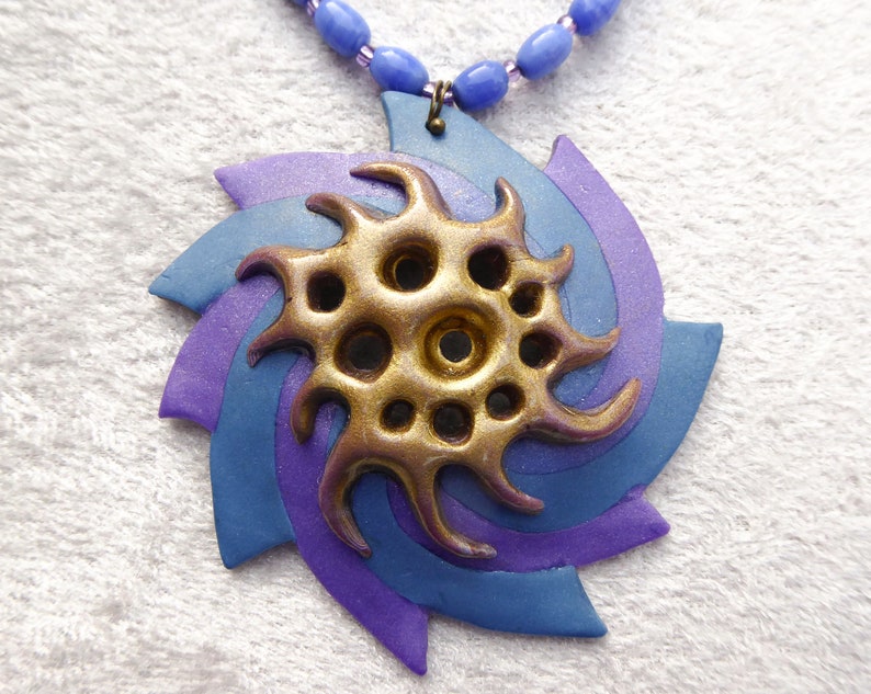 A swirl of blue and sparkly purple polymer clay. Shiny gold polymer clay 3D net. Blue oval glass beads. Bronze colored clasp and chain. image 2