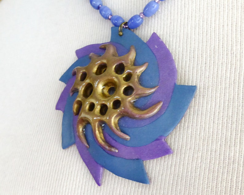 A swirl of blue and sparkly purple polymer clay. Shiny gold polymer clay 3D net. Blue oval glass beads. Bronze colored clasp and chain. image 4