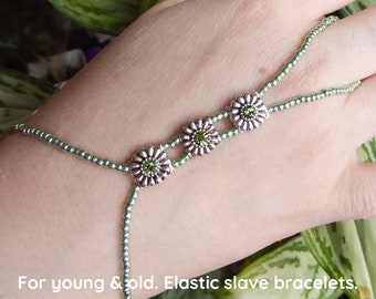 Green rhinestones in silver plated Swarovski flower spacer bars. Pale green metallic, elastic slave bracelet. Finger bracelet. Ring bracelet