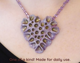 Purple and gold Heart polymer clay pendant necklace. Carved holes with resin in them. Bronze colored clasp and chain. Free form necklace