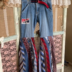 Pode incluir: Jeans azul denim com um cinto vermelho e azul e um padr&atilde;o tie-dye feito de gravatas. O jeans tem um patch com o logotipo da Tommy Jeans na perna esquerda.