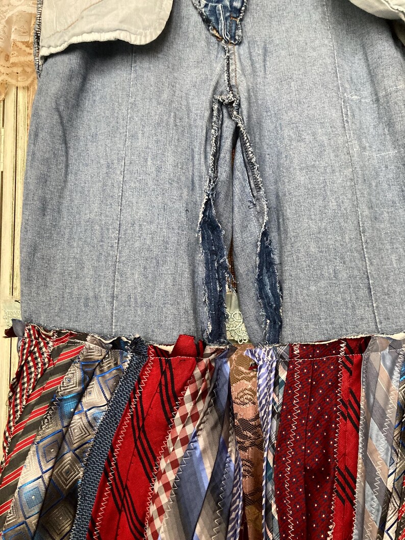 Pode incluir: Uma saia de ganga com uma fenda nas costas, apresentando uma camada inferior de tiras de tecido coloridas costuradas juntas. As tiras de tecido s&atilde;o feitas de v&aacute;rias gravatas estampadas.