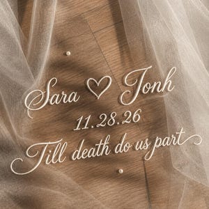 May include: A sheer, ivory wedding veil with embroidered text: "Sara ♡ Jonh", "11.28.26", and "Till death do us part". Small, scattered pearls add delicate detail to the tulle fabric.