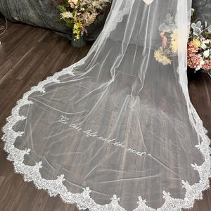 white bridal veil with a delicate lace trim. The veil features the embroidery text "In this life and the next" in a script font. Wedding Veil text embroidery custome