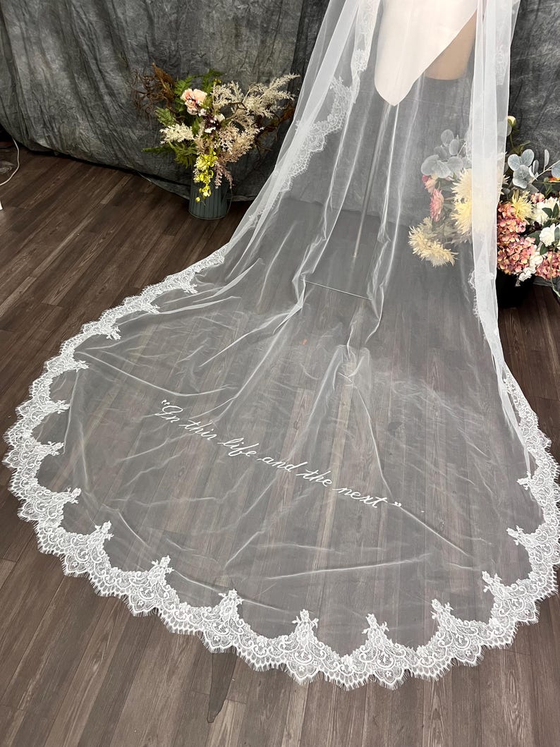 white bridal veil with a delicate lace trim. The veil features the embroidery text "In this life and the next" in a script font. Wedding Veil text embroidery custome